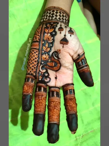 An elegant Arabic-style mehandi design on the back of the hand. The pattern features a peacock, lotus flowers, and hanging bells, creating a graceful and decorative look.
