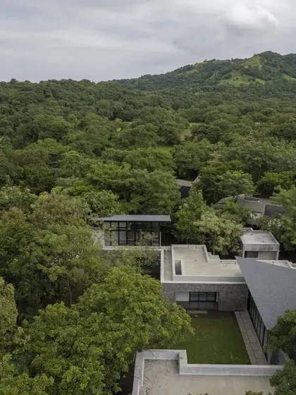 An aerial view of the Villa in a Grove, showing how the structure is carefully placed within the dense tree canopy. The design creates a sense of being nestled in nature, a private world away from everything else.