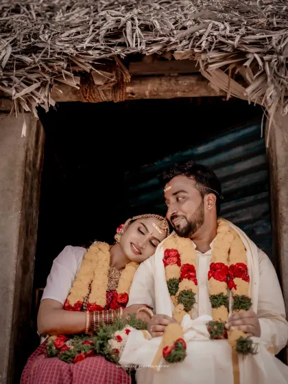 An intimate moment shared by the couple at the doorway of a traditional hut, creating a warm and timeless image.