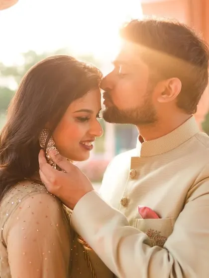 A tender pre-wedding moment, with the groom kissing the bride's forehead under the warm glow of the sun.