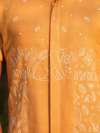 A close-up of the intricate hand-embroidered panther line drawings on our tangerine orange shirt. The design is a narrative of strength, crafted for the man with a 'let's get it done' approach.