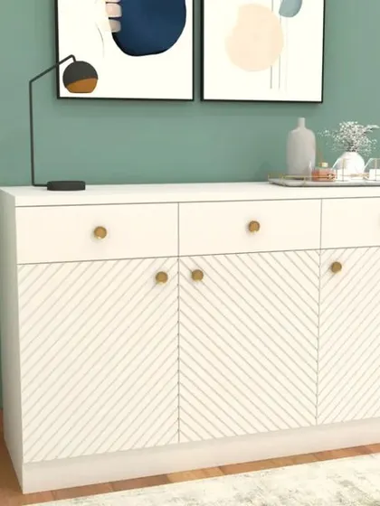 A chic white crockery or storage cabinet with a textured diagonal pattern on the doors and delicate gold knobs. This piece adds a touch of modern elegance to any room.
