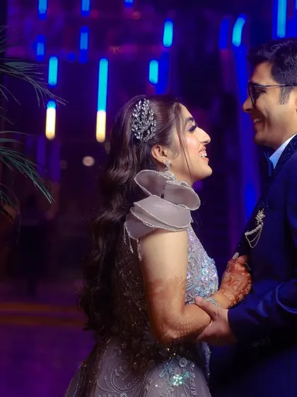 A happy, interactive portrait of an engaged couple, with vibrant blue background lighting adding a modern touch to the celebration.