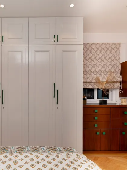 The repetition of the green color in the wardrobe handles and the dresser knobs creates a subtle but cohesive design thread in this bedroom.