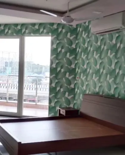 A bedroom with a large green leaf wallpaper, creating a fresh and natural accent wall.