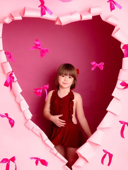 A confident pose from a little Valentine. This portrait showcases the girl's personality as she stands inside the heart-shaped frame, ready for her close-up.