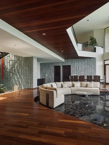 The interior of the mountain home in Chikmagalur, where a sunken lounge creates an intimate space for connection. The double-height windows frame the stunning vistas, making the landscape an integral part of the living experience.