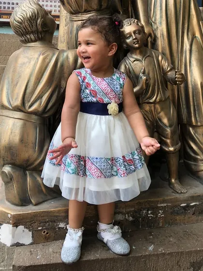 A happy little girl in a unique printed dress with a sheer overlay, proving that my designs are perfect for exploring the world in style.