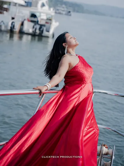 A beautiful solo shot of the bride-to-be, basking in the sun on a yacht, her red gown and hair flowing in the sea breeze.
