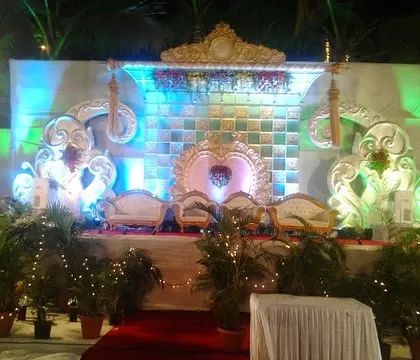 A beautifully lit reception stage at night. The intricate backdrop with traditional motifs is illuminated with colored lights, creating a grand and festive look.
