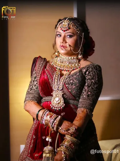 A stunning portrait of the bride in her magnificent red and gold lehenga. Her confident pose and regal attire are highlighted, showcasing her bridal glow.