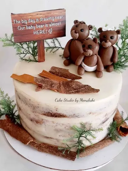 A very cute and rustic baby shower cake. This semi-naked cake is topped with a sweet bear family and a sign that reads, "Our baby bear is almost here!"