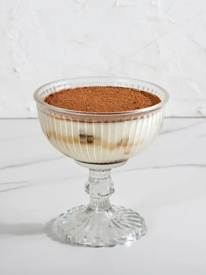 The Classic Tiramisu presented in an elegant glass goblet, with its distinct layers of cream and coffee-soaked biscuits visible.