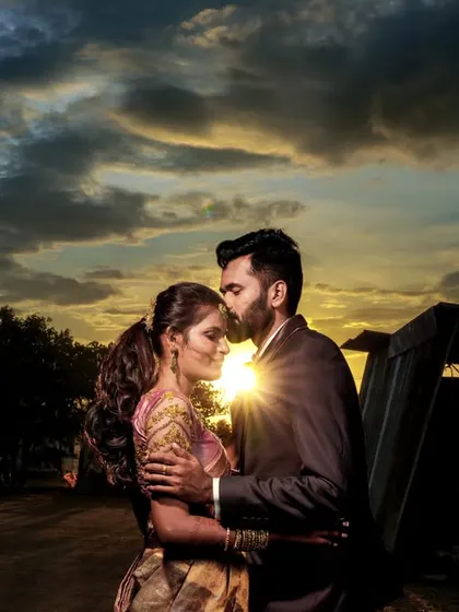 A dramatic sunset silhouette captured in Palladam, with the groom kissing the bride's forehead.