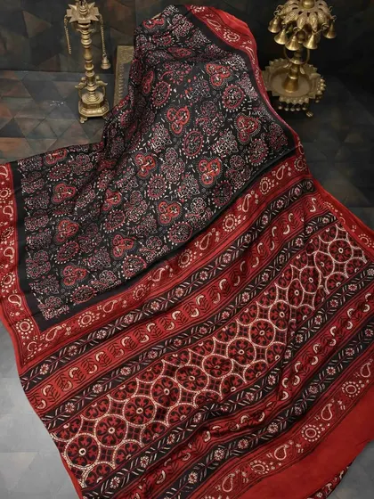 A stunning black and red Ajrakh printed saree. The intricate geometric and floral patterns are created using traditional block printing techniques from Kutch.