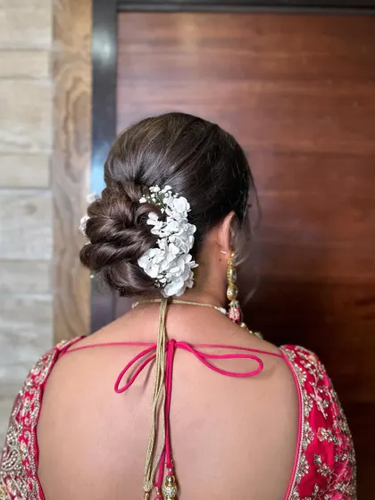 This fresh wedding bun is styled with delicate white flowers and baby's breath. It's a romantic and timeless choice for any bride on her wedding day.