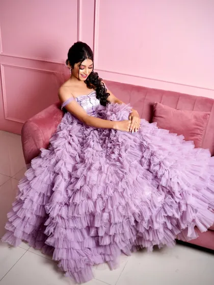Feel like a princess in this lavender ruffle gown. It's one of my most popular rental pieces, shown here on our plush pink sofa against a matching pink wall, creating a dreamy, monochrome look.