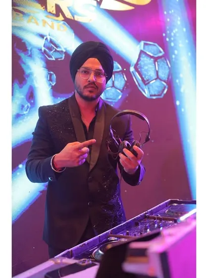 Our DJ is the backbone of our sound, mixing tracks seamlessly to keep the energy high all night. He's pointing at the decks, ready to drop the next banger.
