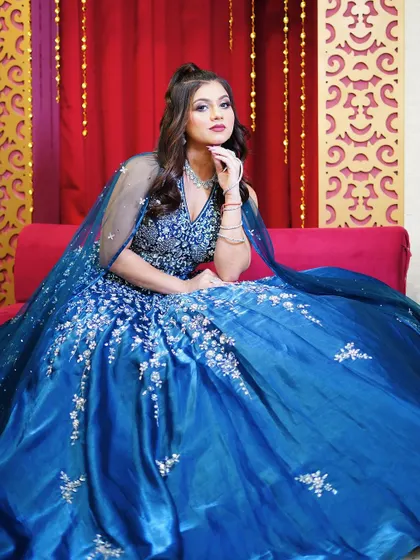 A close-up of the blue ball gown, highlighting the detailed bodice and flowing cape.