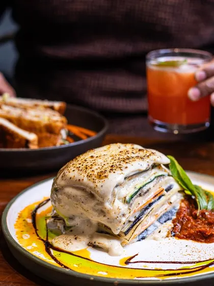 A cozy dinner scene featuring my vegetable lasagna and a refreshing cocktail. It shows that my food is perfect for a relaxed evening meal.