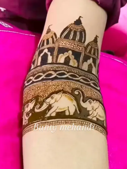 A detailed armband showcasing a procession of elephants below a beautifully drawn temple or palace structure. This is a perfect example of architectural mehandi.