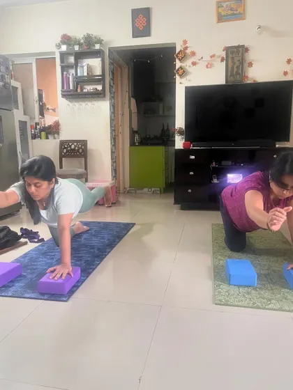 A duplicate of the previous image, showing clients using yoga blocks for support in a balancing table pose to enhance stability and form.