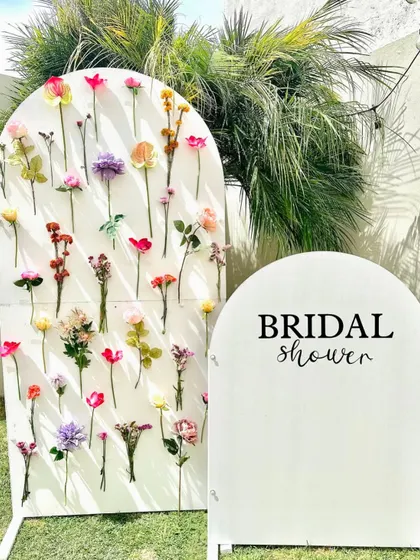 A minimalist and modern bridal shower setup with a flower wall backdrop, perfect for an outdoor celebration.