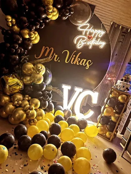 A personalized black and gold birthday theme with the celebrant's name and initials in lights.