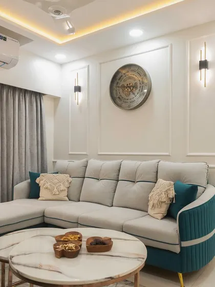 A shot of the comfortable L-shaped sofa, with elegant wall molding and modern sconce lighting that adds a touch of sophistication.