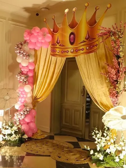 A royal entrance for a princess-themed party, with a giant crown prop and a golden curtain.