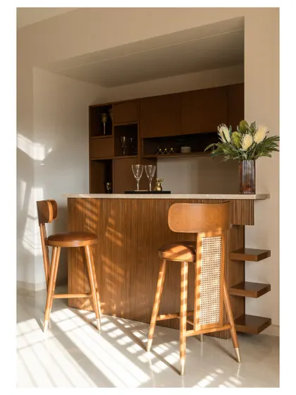 We designed a sleek home bar with a fluted wood front and a clean white countertop. The matching bar stools with cane backs tie the whole look together.