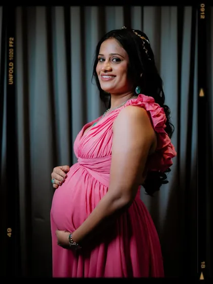 A happy and confident portrait of the mother-to-be. Her direct, smiling gaze at the camera combined with the classic pose of holding her baby bump makes for a joyful and timeless maternity photograph.