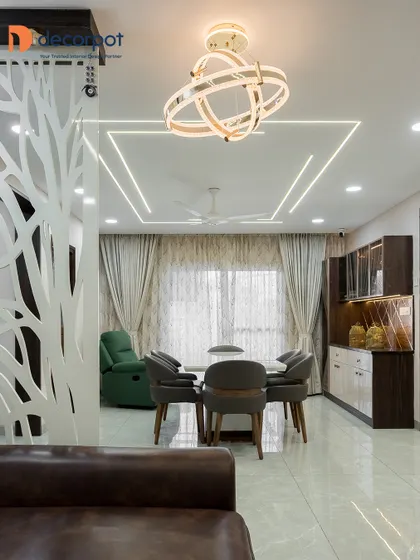 An open-concept living and dining area defined by a striking white CNC-cut partition. The space is illuminated by a modern chandelier and recessed ceiling lights, creating a bright and airy feel.