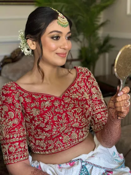 The bride's happy reflection says it all. We chose a soft, low bun with face-framing tendrils to create a look that felt like her, just elevated for her special day.
