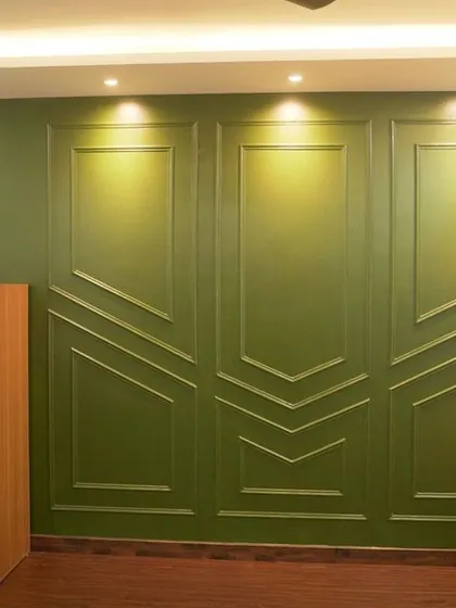 A living room with a bold green accent wall featuring decorative molding. The design is a perfect blend of classic and contemporary styles.