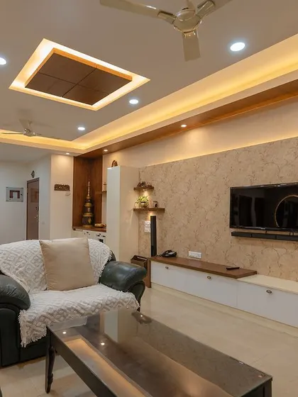 A closer view of the living room, showcasing the elegant TV unit and the nearby pooja mandir. The design proves that functionality and spirituality can coexist beautifully.