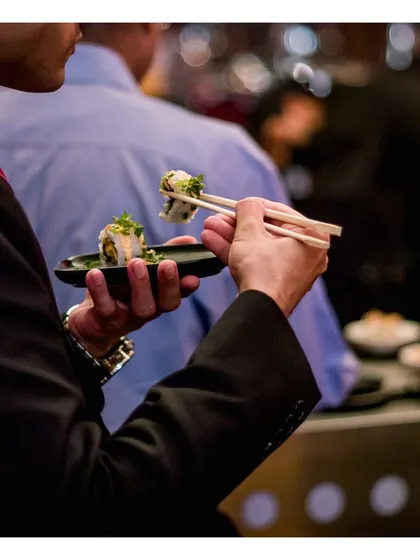 A guest enjoys a freshly prepared sushi roll, showcasing the high-quality, authentic experience we provide at our Japanese food stations.