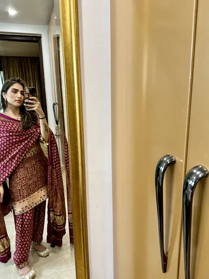 A mirror selfie in a traditional maroon printed suit, perfect for a small festive gathering or puja.