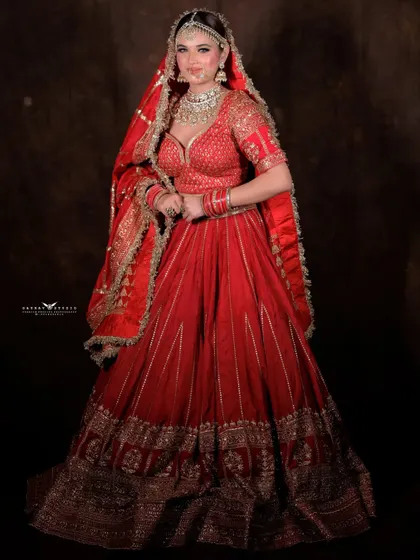 A slightly different full-length pose, showing the bride's complete outfit. The focus is on the traditional silhouette and the rich details of the lehenga.