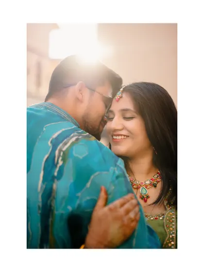 An intimate embrace between the couple, backlit by the sun, during their Haldi celebration.