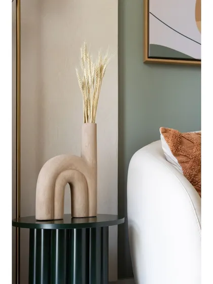 This sculptural vase on a fluted side table is an example of how we use decor to reinforce the design theme. The deep green of the table adds a touch of depth to the neutral color scheme.