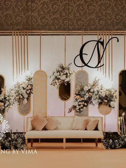 A classic and elegant reception setup symbolizing everlasting love. The stage features a modern, minimalist backdrop with custom monograms, floral arrangements, and soft lighting.