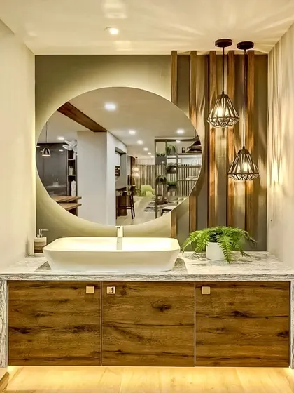 This vanity area features a large, backlit round mirror that serves as a beautiful focal point. The wooden cabinet and vessel sink create a modern yet natural look.
