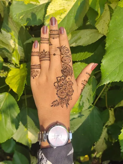 Sometimes, less is more. This is an example of a modern, minimalist henna design on the back of the hand, featuring a delicate floral vine and simple finger details.