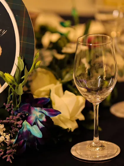 A detailed view of the personalized table sign for "Vyaan's 1st Birthday," featuring the adorable teddy bear motif. The surrounding florals and elegant glassware showcase our commitment to a polished and complete look.