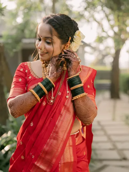 The bride adjusts her traditional earrings, her intricate henna on display.
