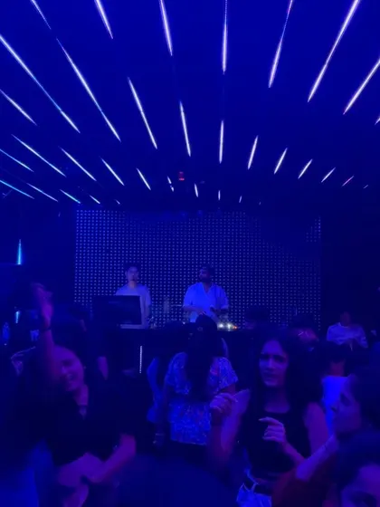 A full view of the dance floor under the cool blue lights, with everyone lost in the music.