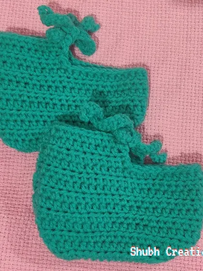 A pair of soft, hand-crocheted teal baby booties with simple tie closures to keep them snug on little feet.