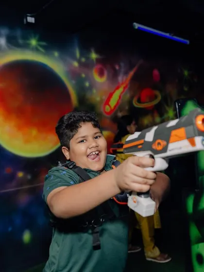 The pure joy of the game. A young player is all smiles as he gets ready to tag his opponents in our space-themed arena.
