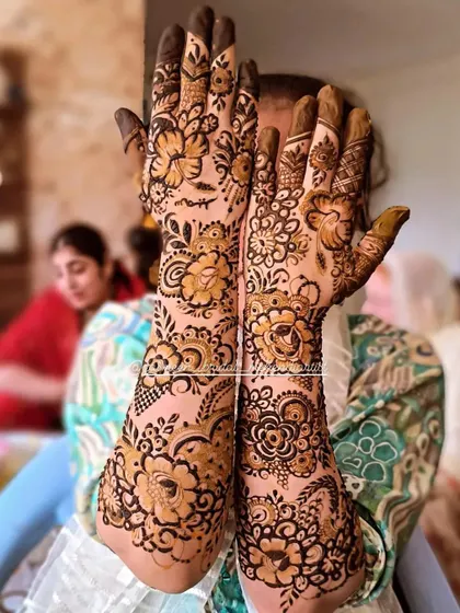 A happy client showing off her designer floral mehendi, which mixes different flower sizes and styles.